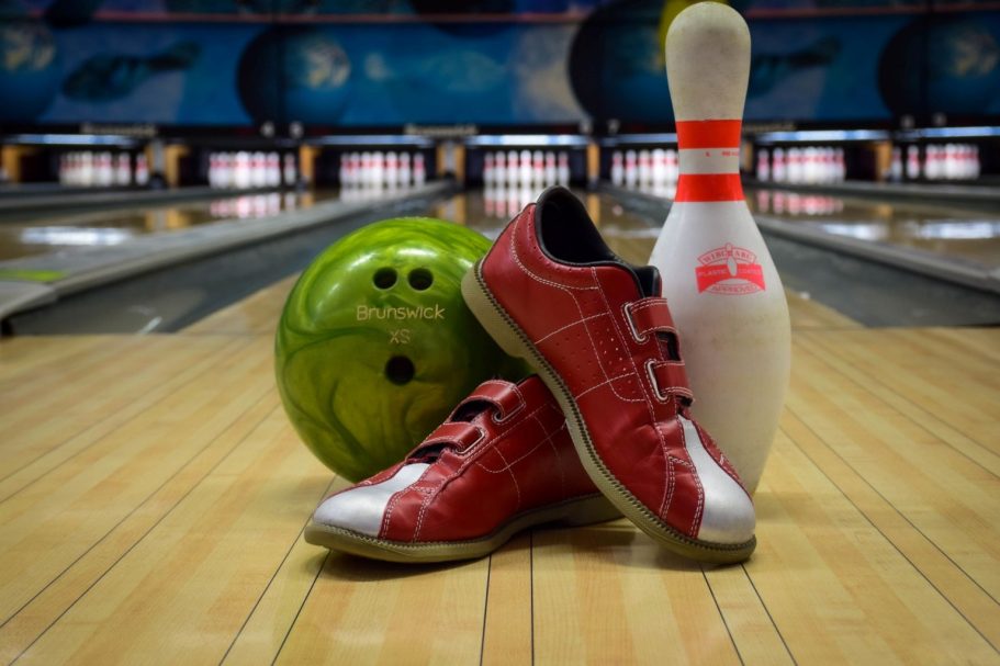 Bowling https://www.bowling-auxerre.com/ Chaussures de bowling rouges, boule verte et quille blanche sur une piste de bowling.