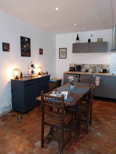 Cuisine lumineuse avec une table en bois, des chaises et un buffet, décorée sobrement.